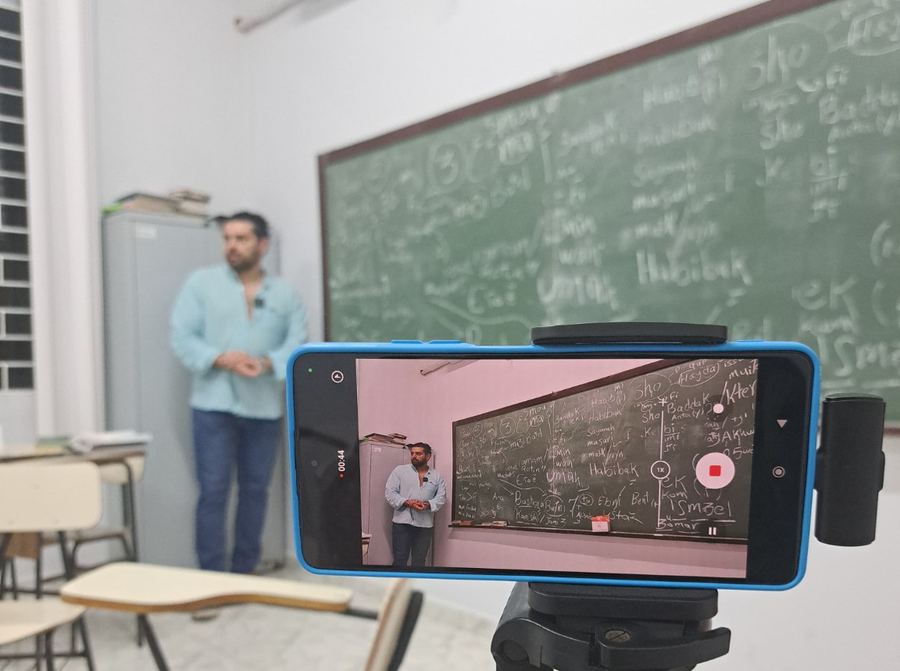 Aula de árabe sendo gravada, com a lousa preenchida de vocabulário em dialeto sírio-libanês